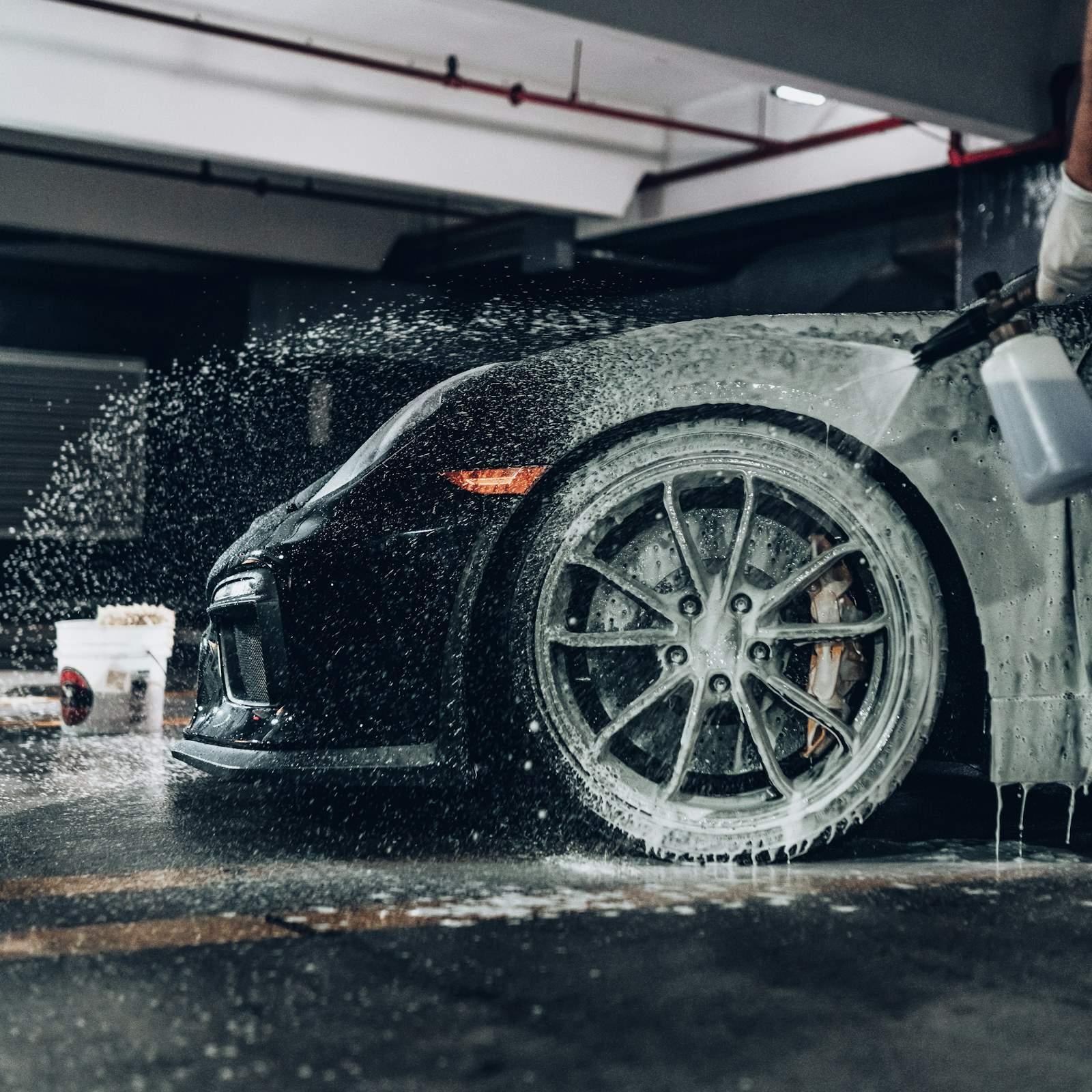 Snow foam being sprayed over a black sports car