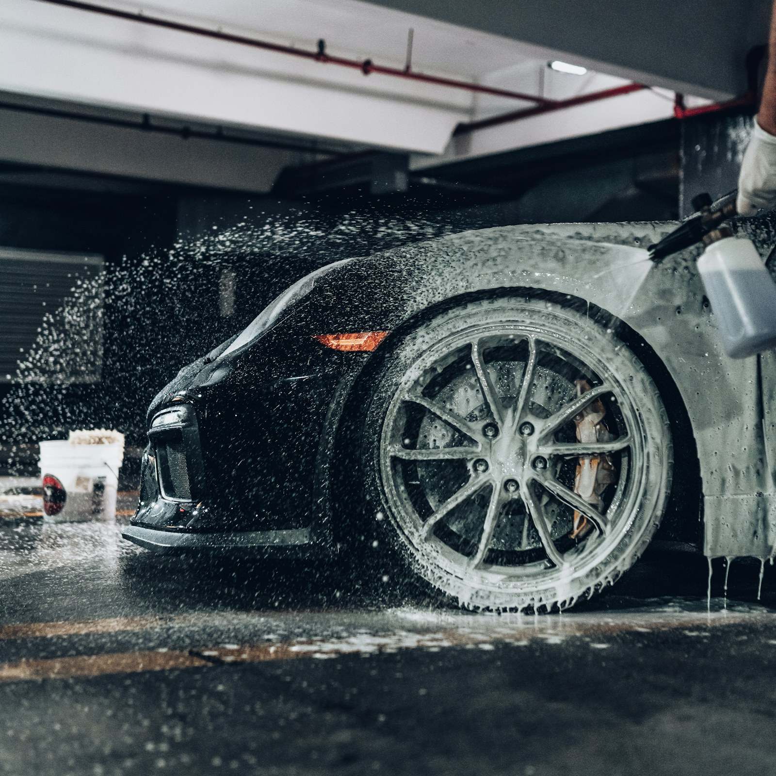 Snow foam being sprayed over a black sports car