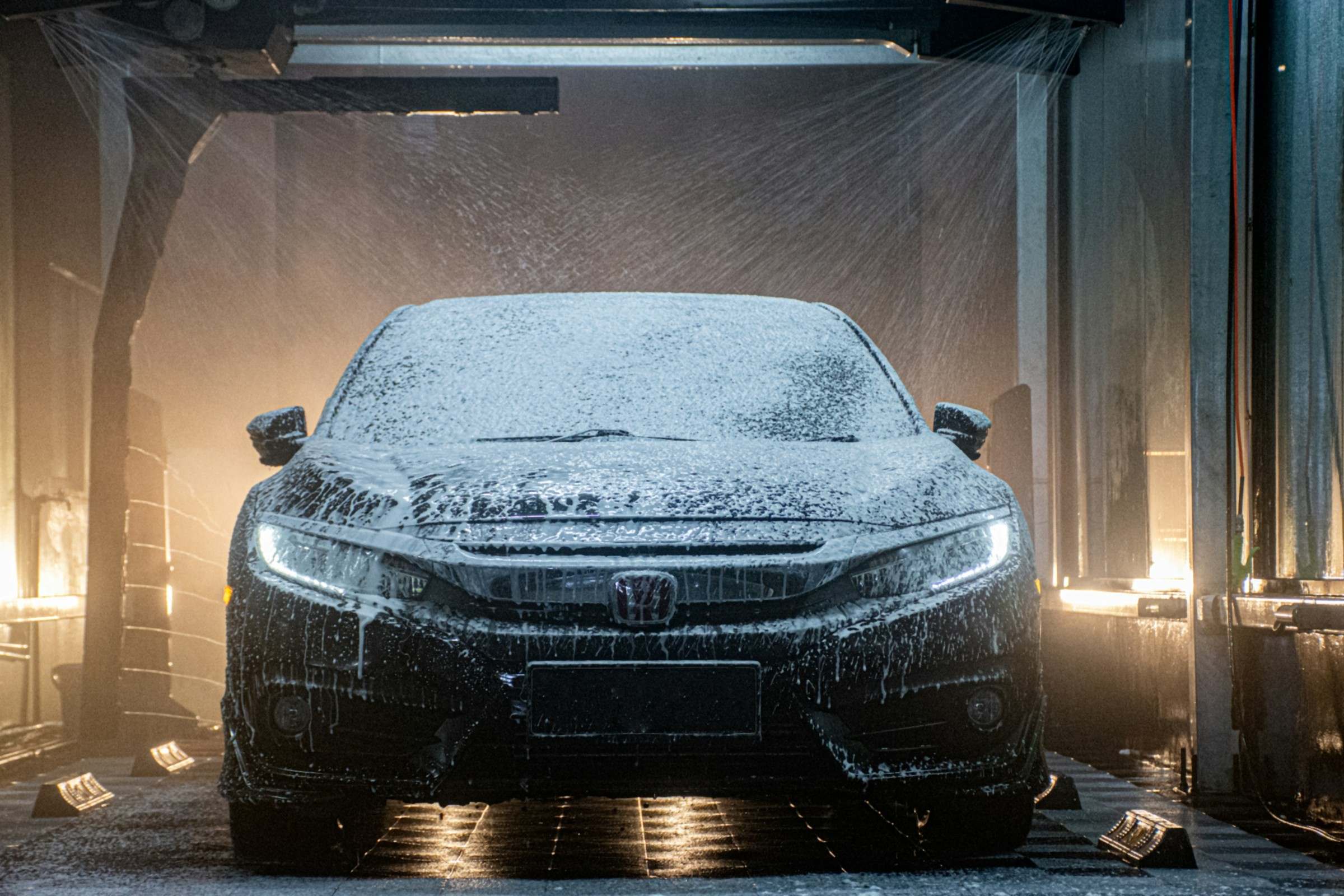 Car covered in thick foam inside a hand car wash bay