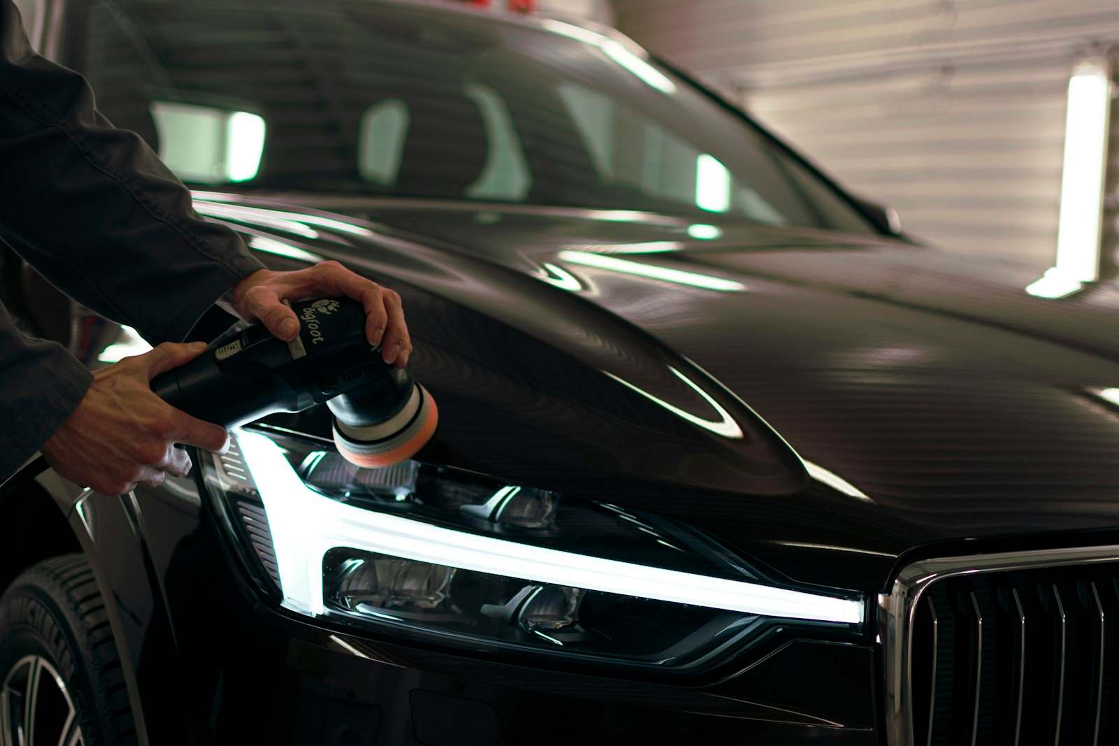 Polishing the bonnet of a black car next to its headlight